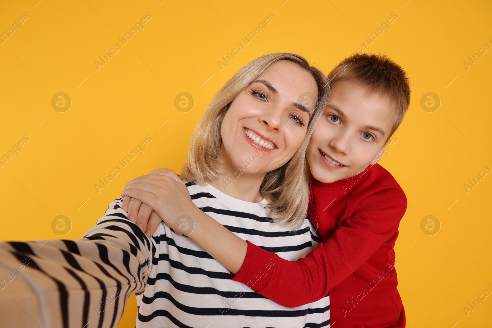 Photo of Happy mother and son taking selfie on orange background