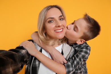 Photo of Happy mother and son taking selfie on orange background