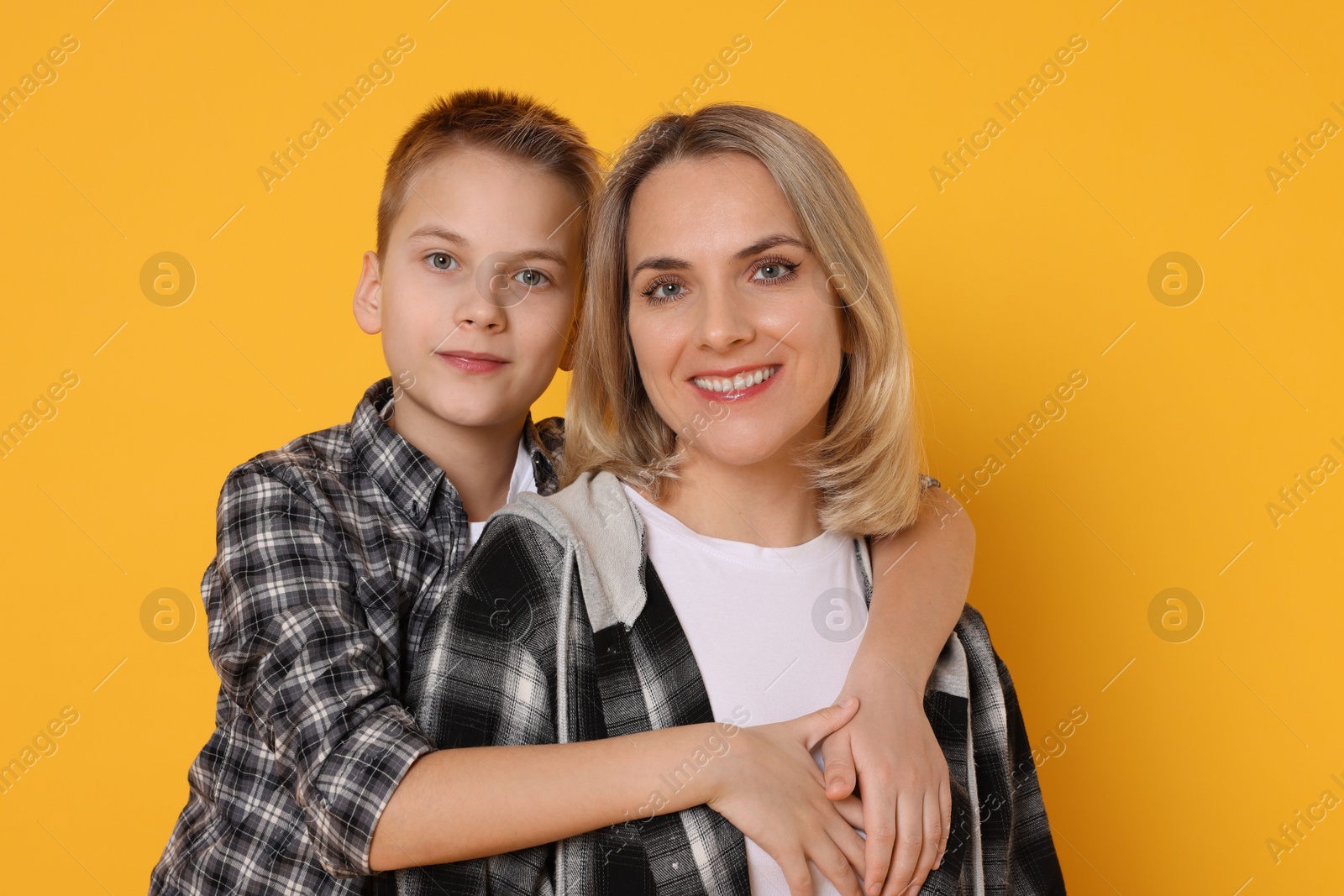 Photo of Mother and son hugging on orange background