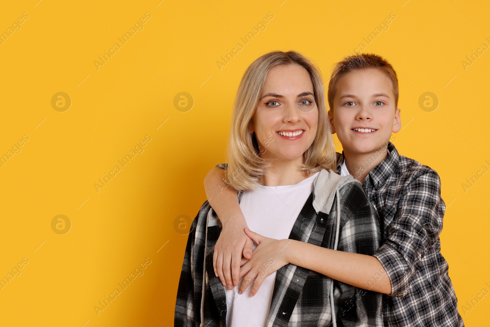 Photo of Mother and son hugging on orange background. Space for text