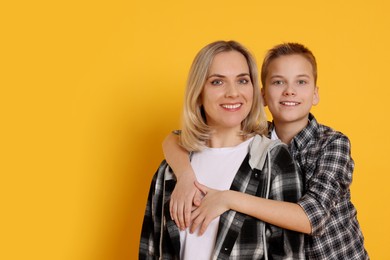 Photo of Mother and son hugging on orange background. Space for text