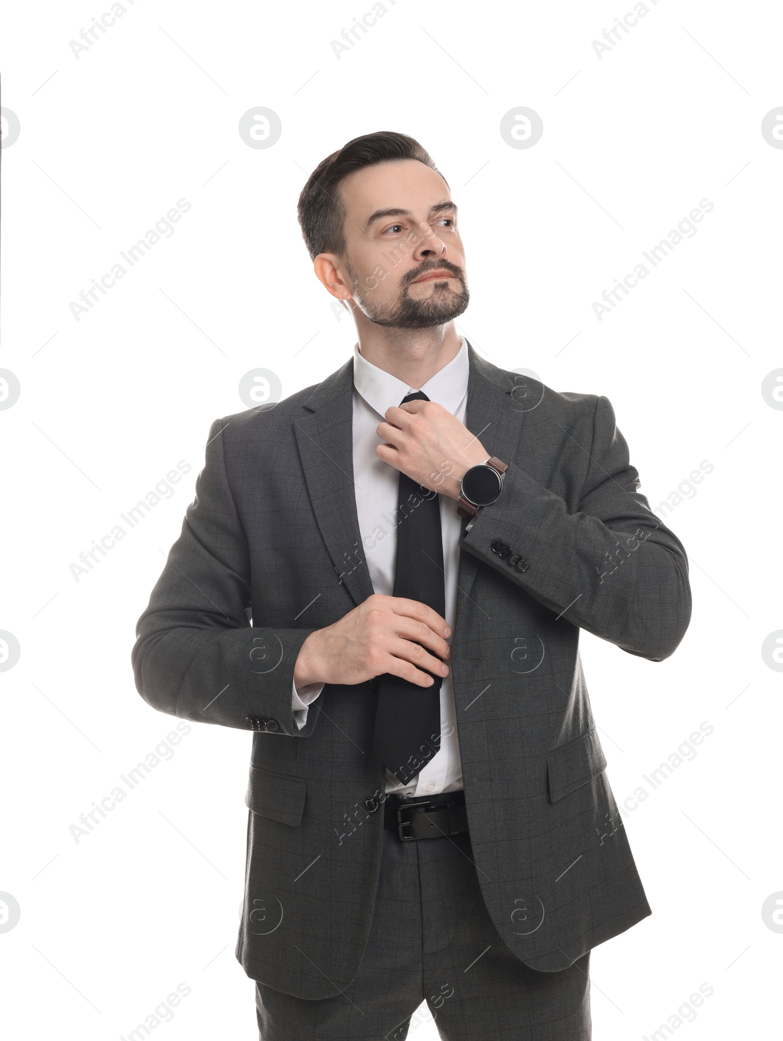 Photo of Confident man in classic suit straightening tie on white background