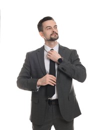 Photo of Confident man in classic suit straightening tie on white background