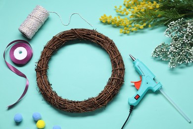 Photo of Hot glue gun and handicraft materials on light blue background, flat lay