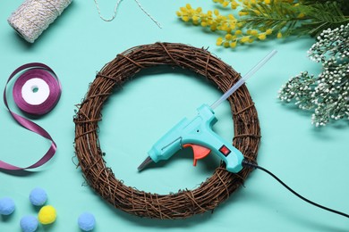 Photo of Hot glue gun and handicraft materials on light blue background, flat lay