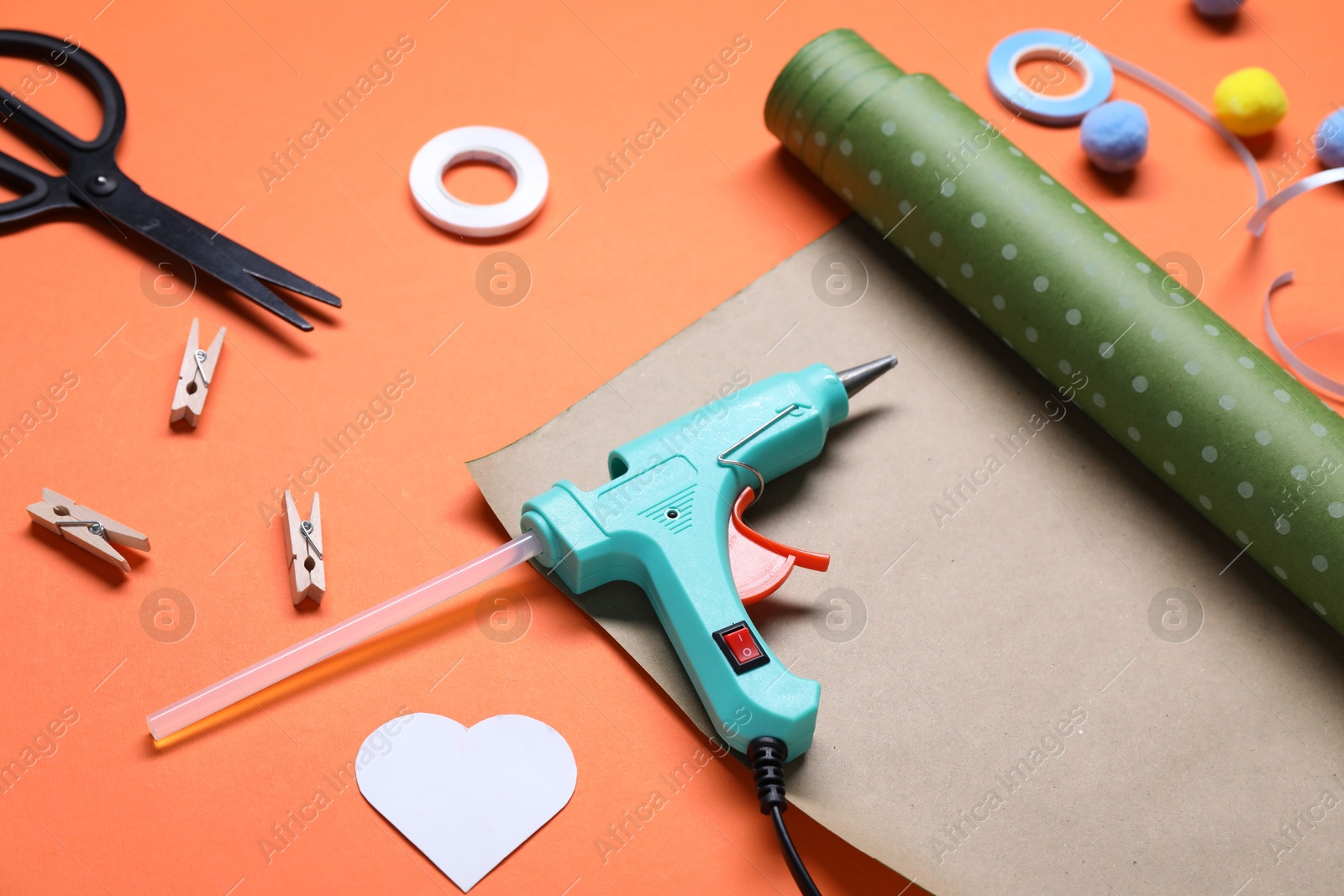 Photo of Hot glue gun and handicraft materials on orange background