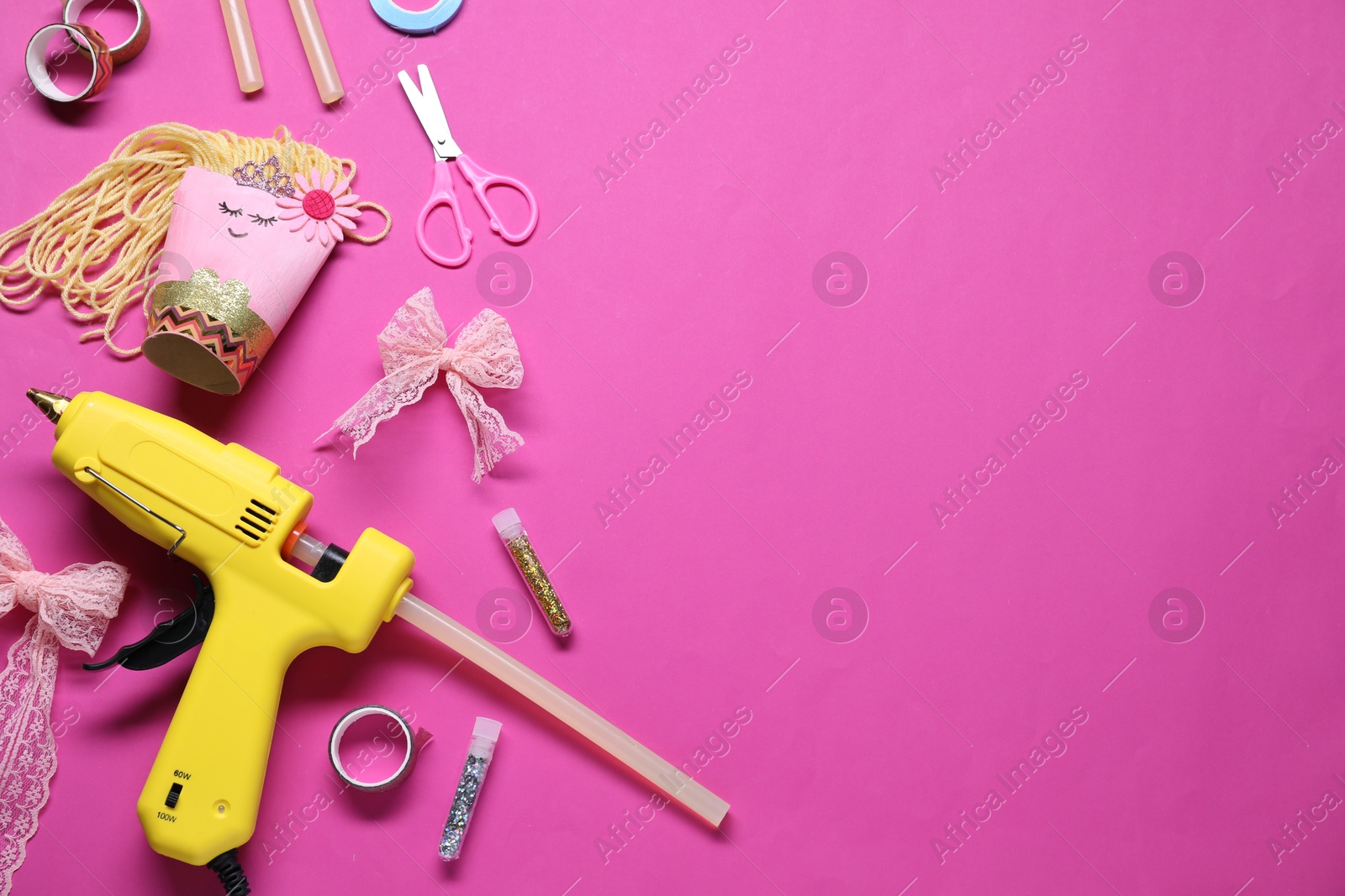 Photo of Hot glue gun and handicraft materials on bright pink background, flat lay. Space for text