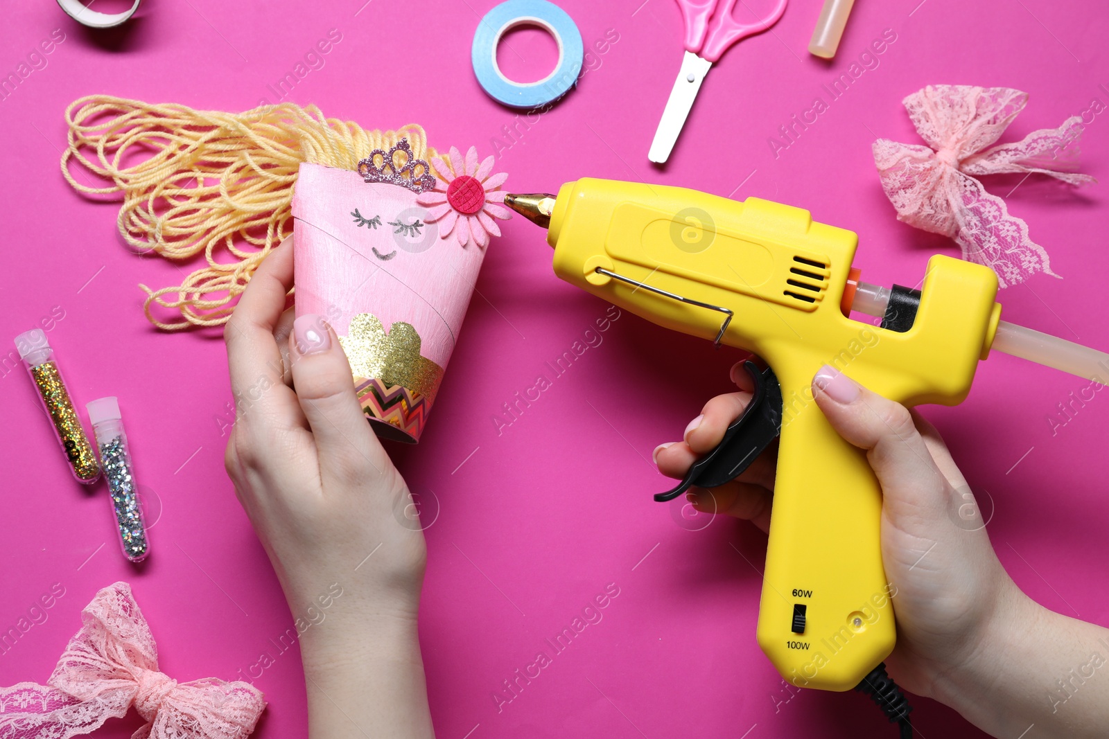 Photo of Woman with hot glue gun making craft on bright pink background, top view