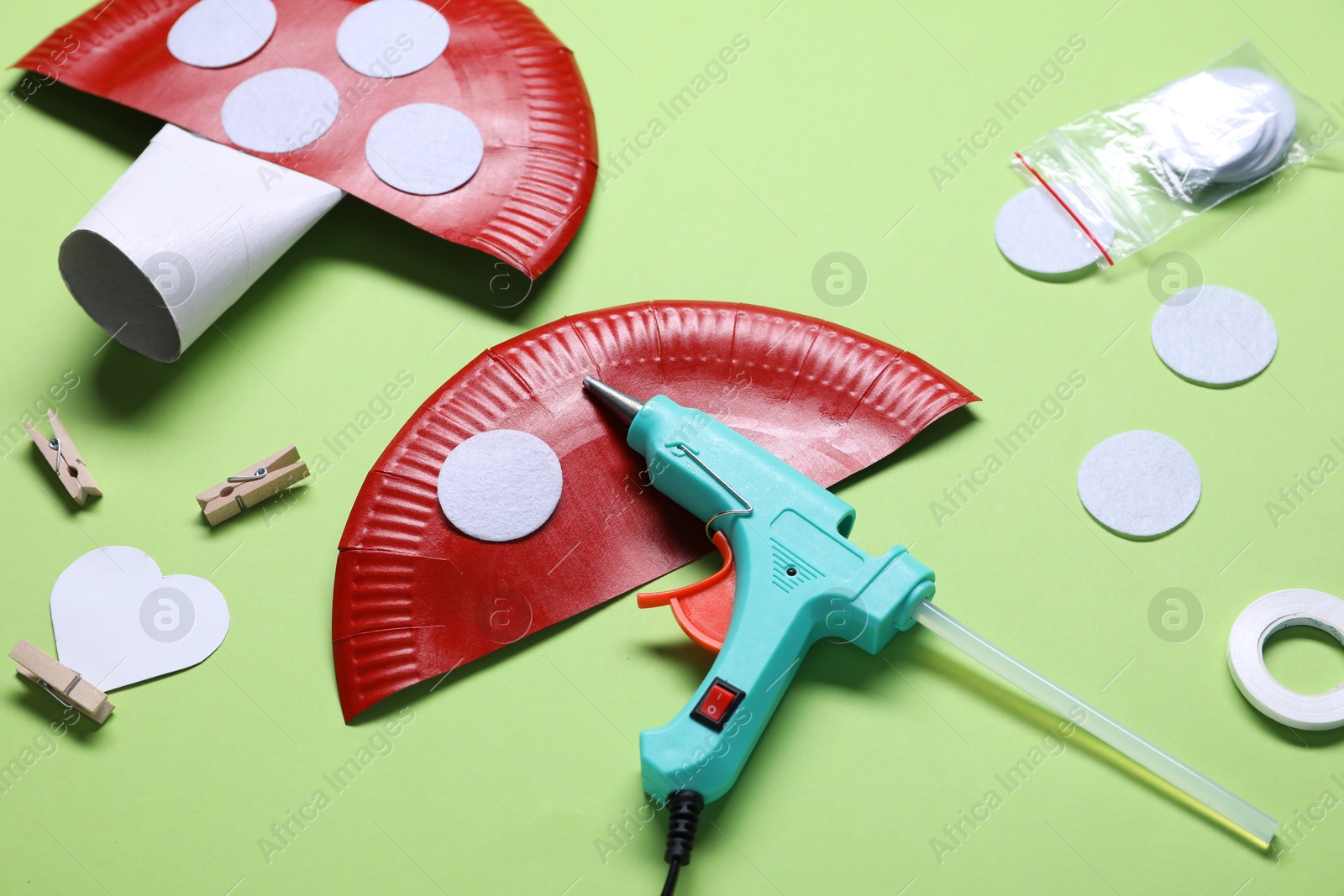 Photo of Hot glue gun and handicraft materials on green background