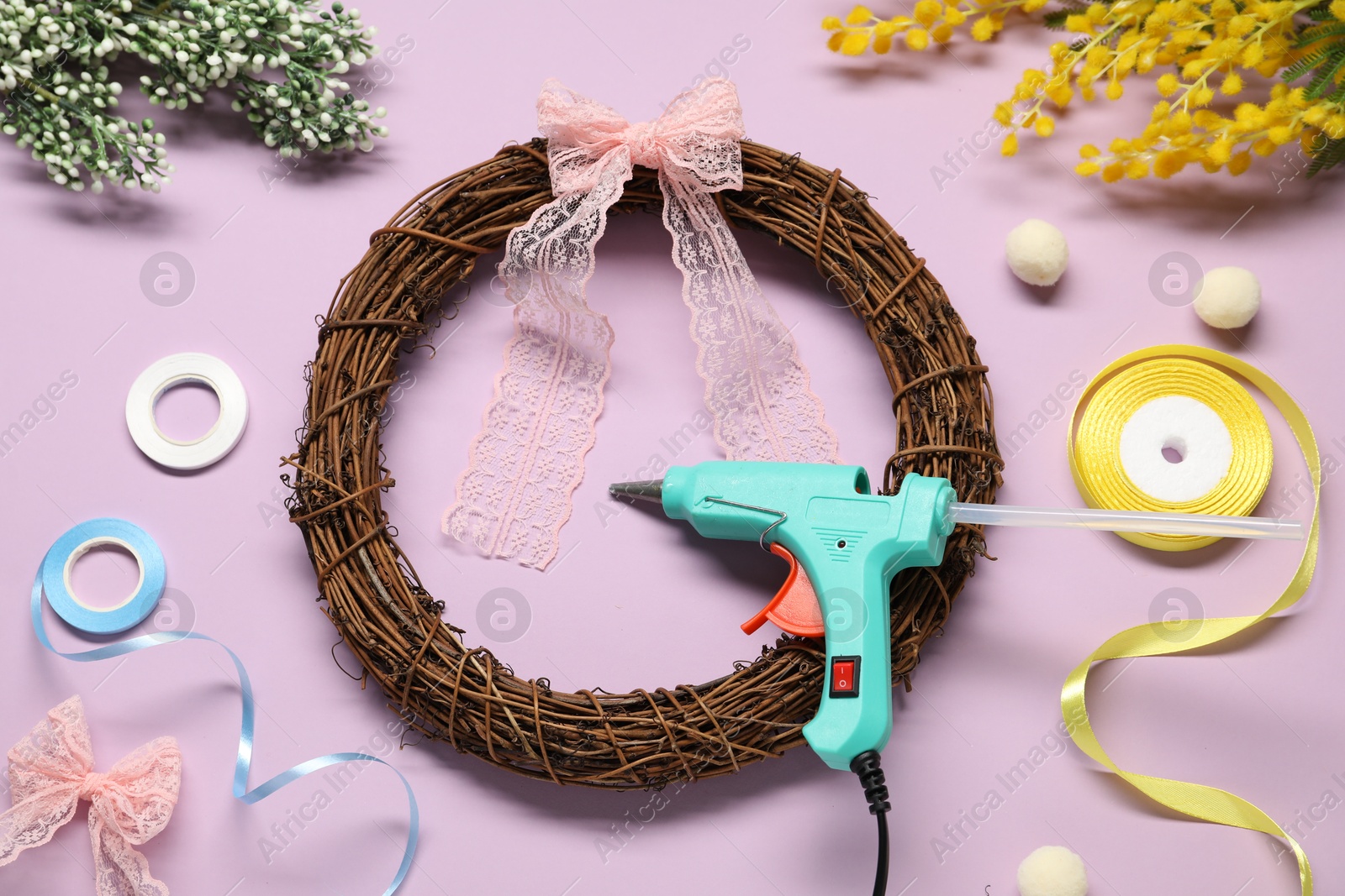 Photo of Hot glue gun and handicraft materials on lilac background, flat lay