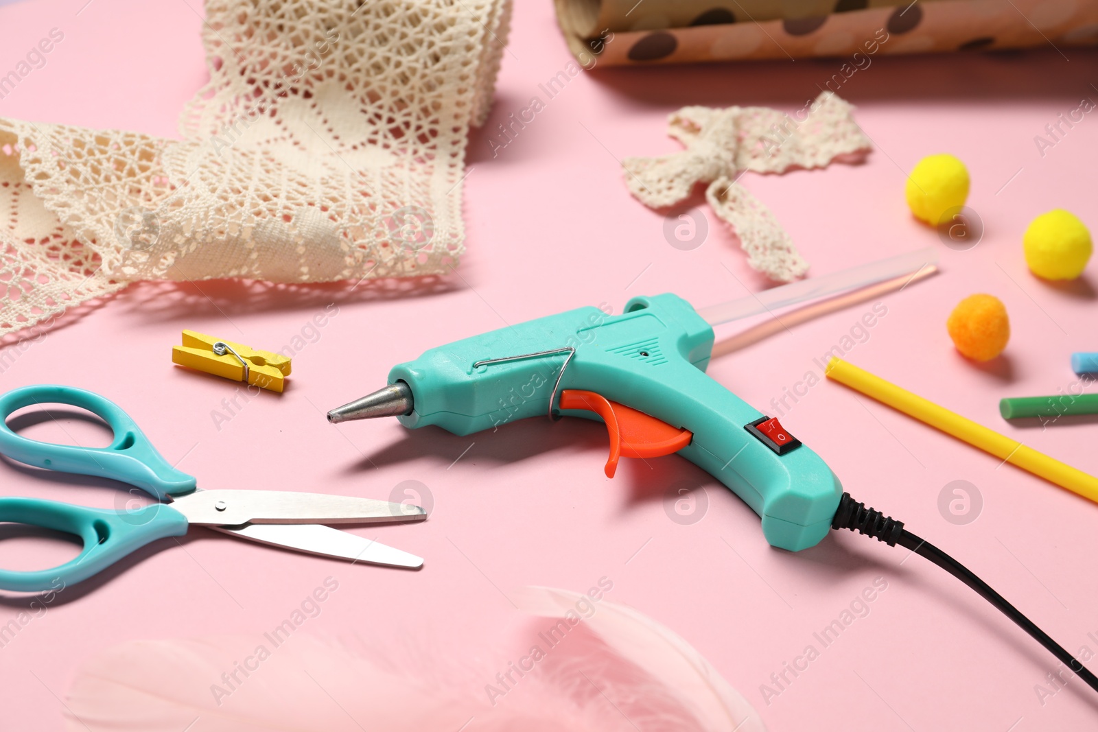 Photo of Hot glue gun and handicraft materials on pink background