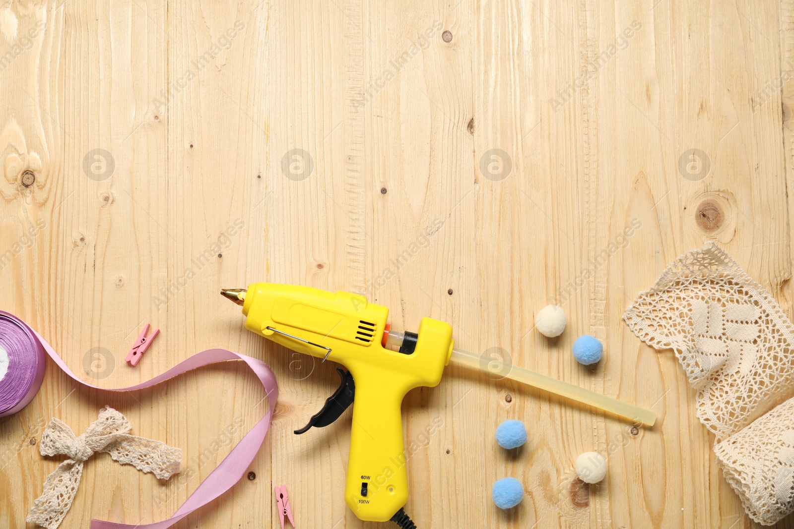 Photo of Hot glue gun and handicraft materials on wooden background, flat lay. Space for text