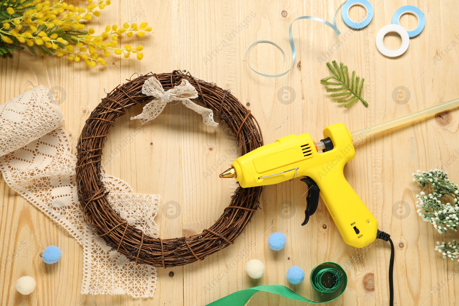 Photo of Hot glue gun and handicraft materials on wooden background, flat lay