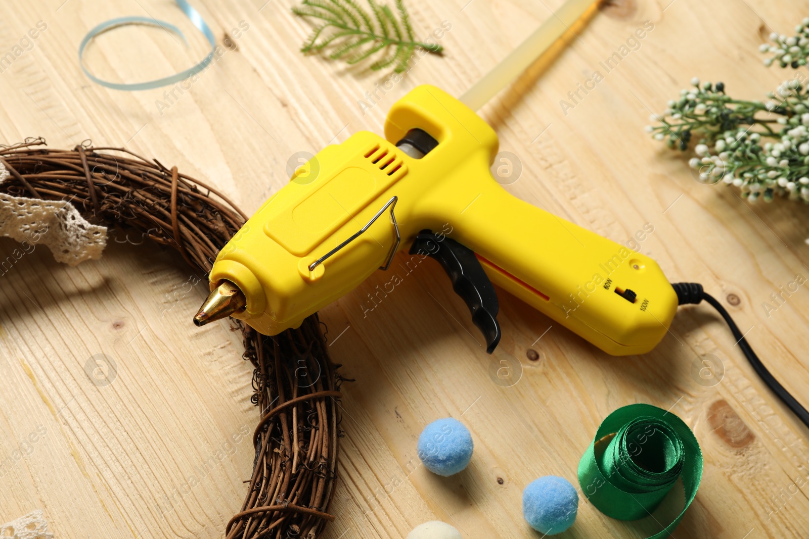 Photo of Hot glue gun and handicraft materials on wooden background, closeup