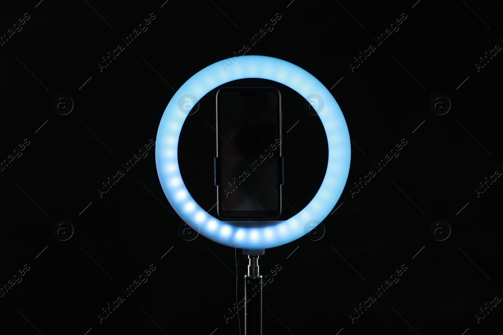 Photo of Ring lamp with smartphone on black background