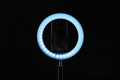 Photo of Ring lamp with smartphone on black background