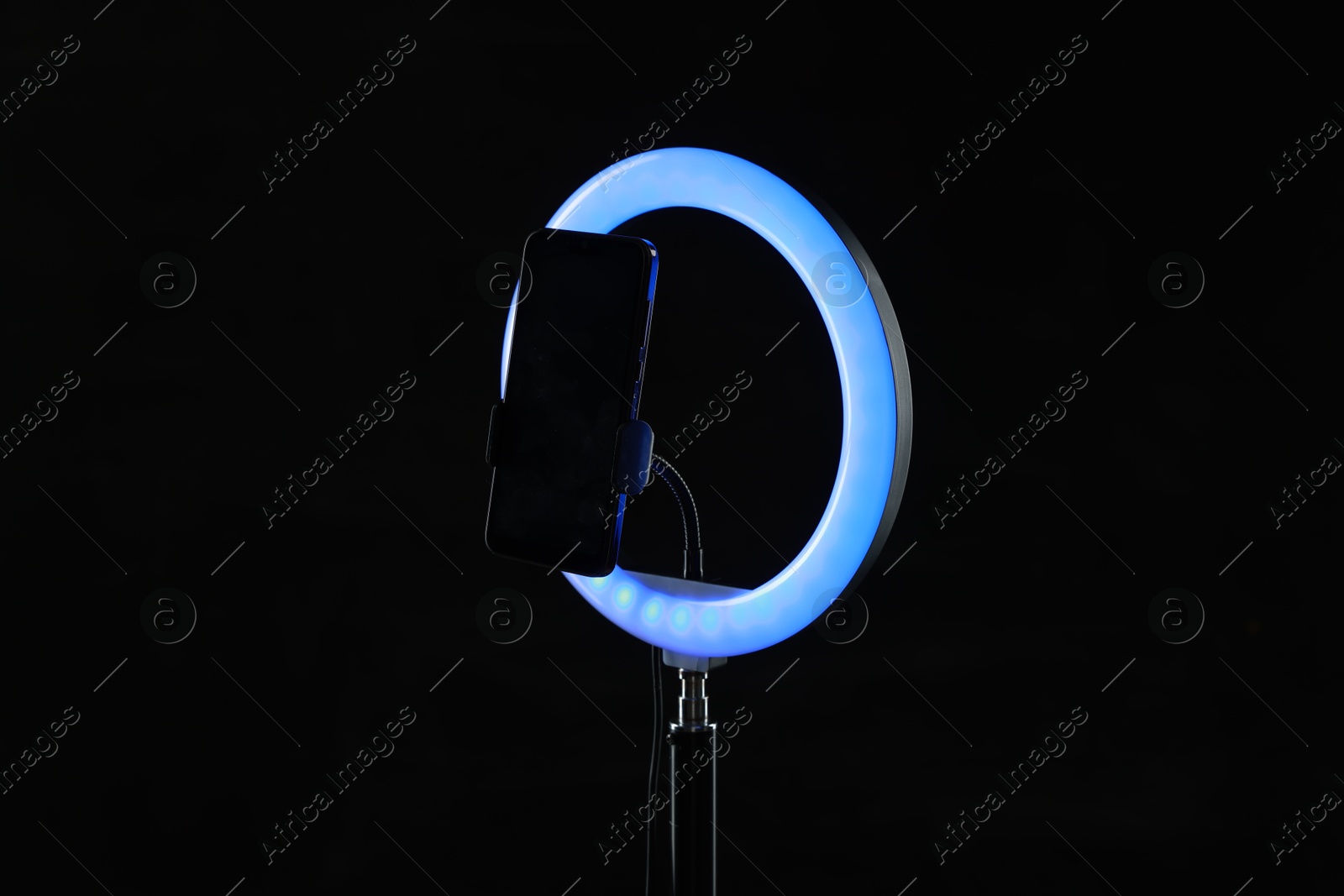 Photo of Ring lamp with smartphone on black background