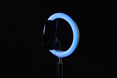 Photo of Ring lamp with smartphone on black background