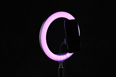 Photo of Ring lamp with smartphone on black background