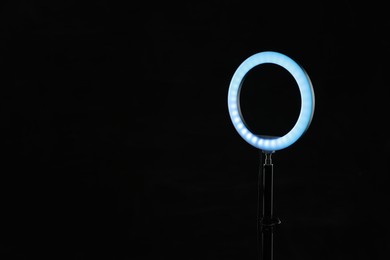 Photo of Ring lamp on stand against black background, space for text