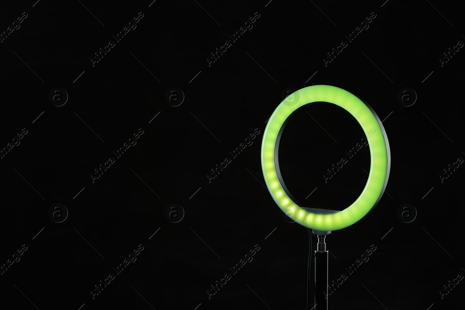 Photo of Ring lamp on stand against black background, space for text