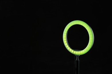 Photo of Ring lamp on stand against black background, space for text