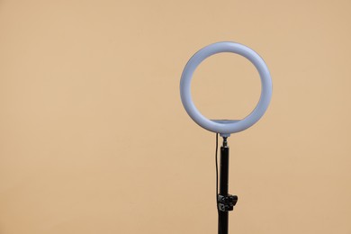 Photo of Ring lamp on stand against beige background, space for text