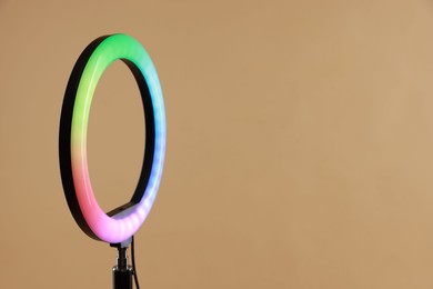 Photo of Ring lamp on stand against beige background, closeup. Space for text