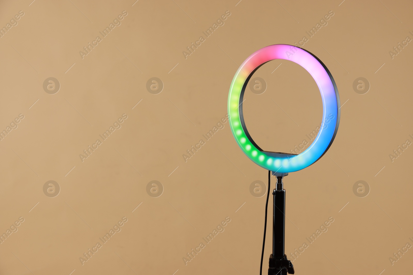 Photo of Ring lamp on stand against beige background, space for text