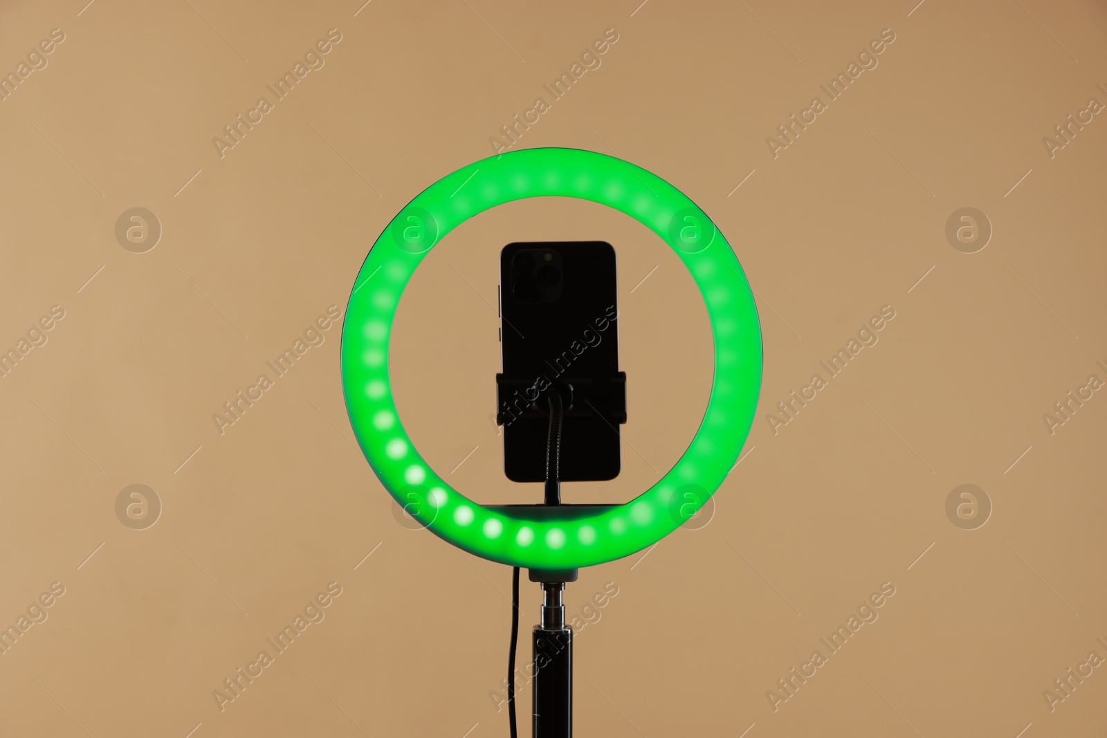 Photo of Ring lamp with smartphone on beige background