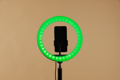 Photo of Ring lamp with smartphone on beige background