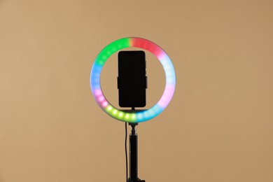 Photo of Ring lamp with smartphone on beige background