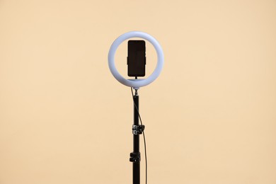 Photo of Ring lamp with smartphone on beige background