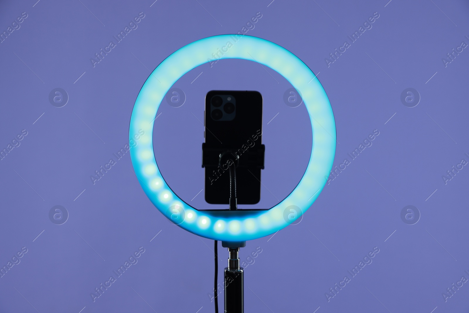 Photo of Ring lamp with smartphone on purple background