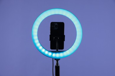 Photo of Ring lamp with smartphone on purple background