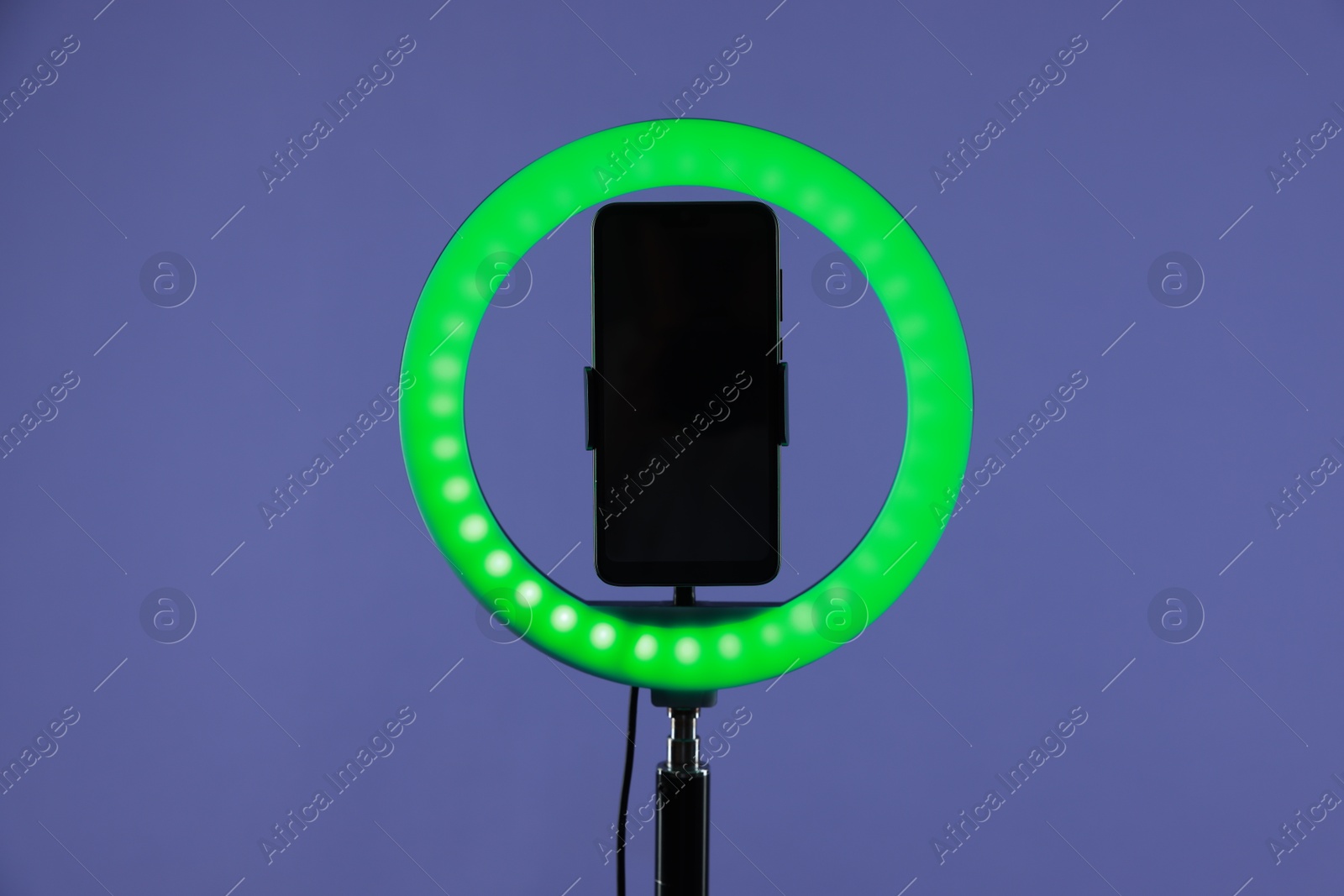 Photo of Ring lamp with smartphone on purple background