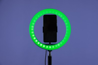 Photo of Ring lamp with smartphone on purple background