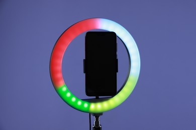 Photo of Ring lamp with smartphone on purple background