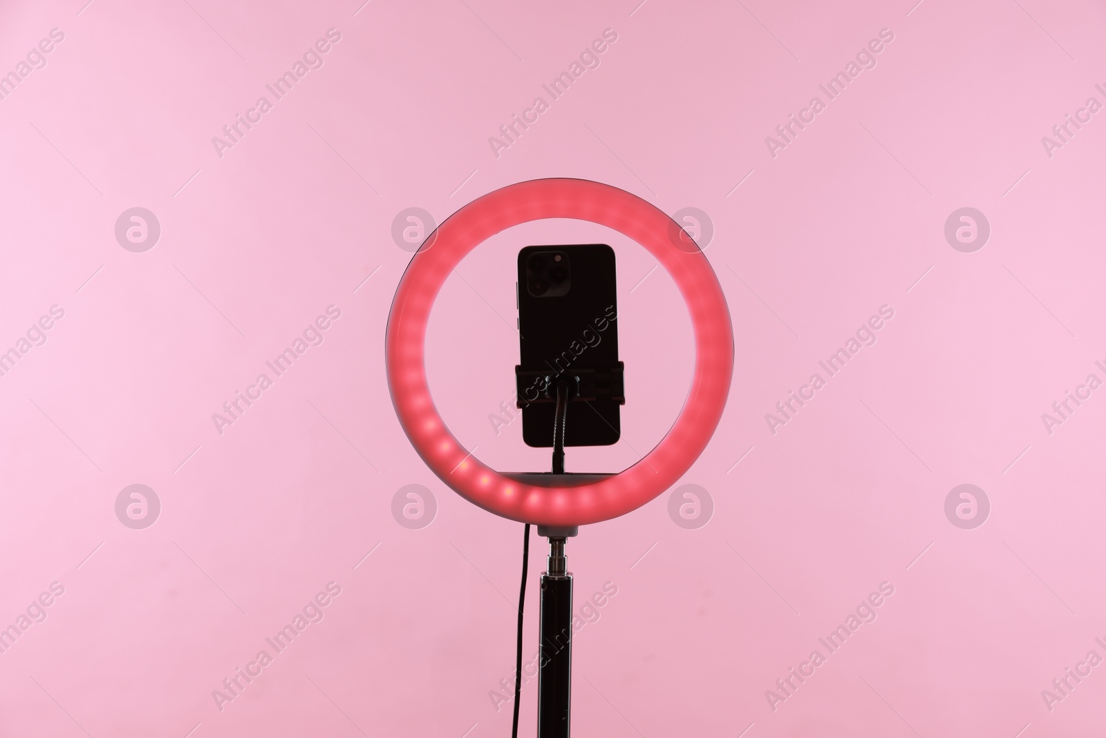 Photo of Ring lamp with smartphone on pink background