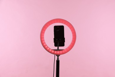 Photo of Ring lamp with smartphone on pink background