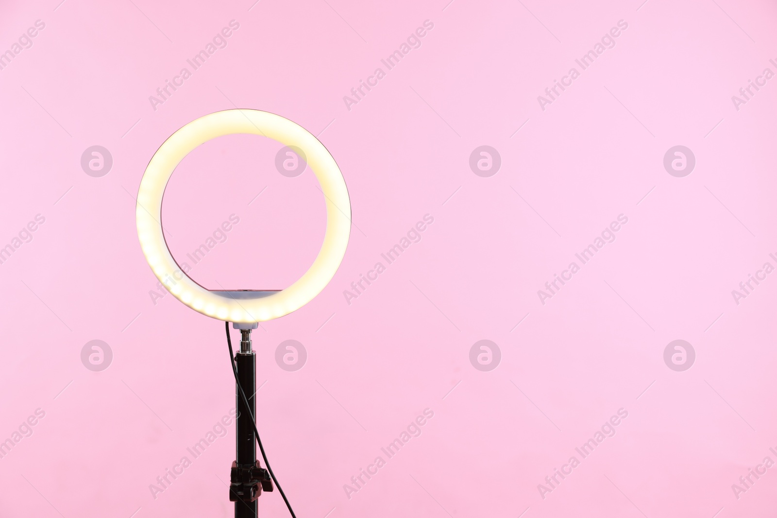 Photo of Ring lamp on stand against pink background, space for text