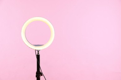 Photo of Ring lamp on stand against pink background, space for text