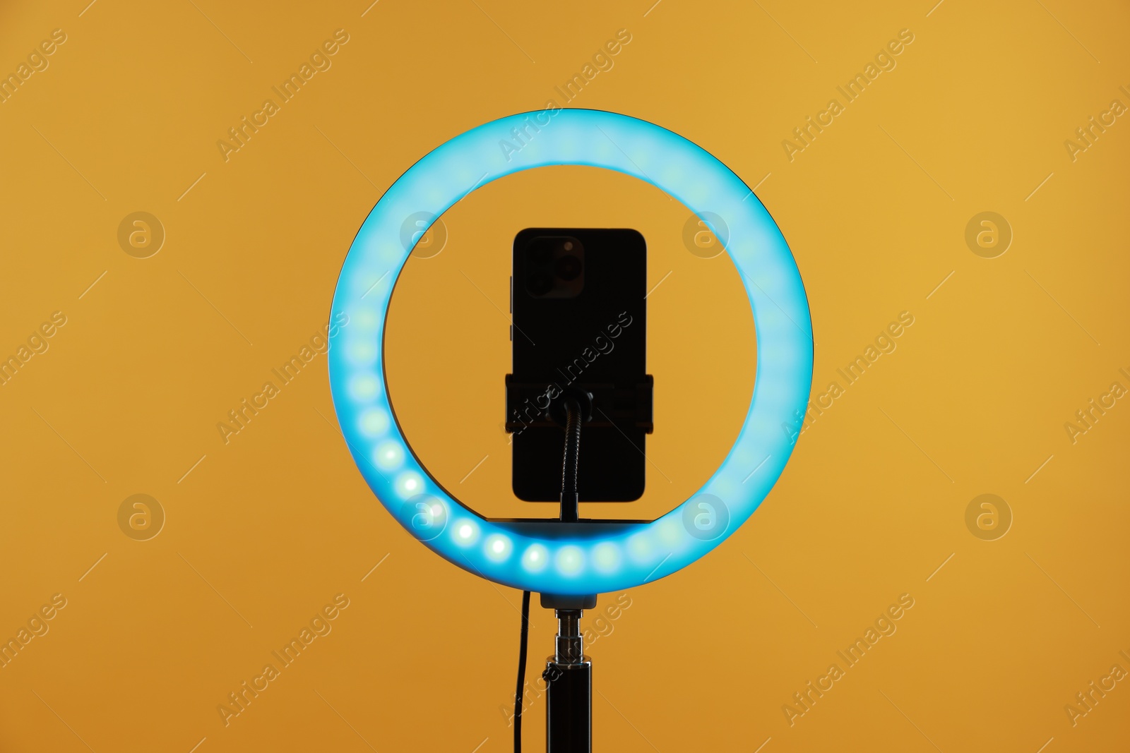 Photo of Ring lamp with smartphone on orange background