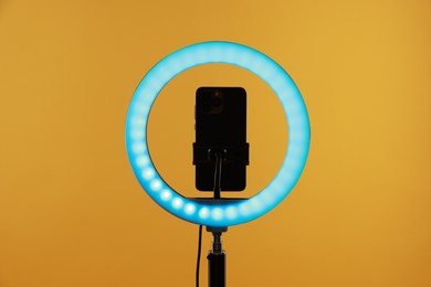 Photo of Ring lamp with smartphone on orange background