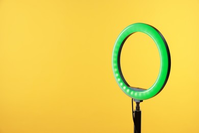 Photo of Ring lamp on stand against yellow background, space for text