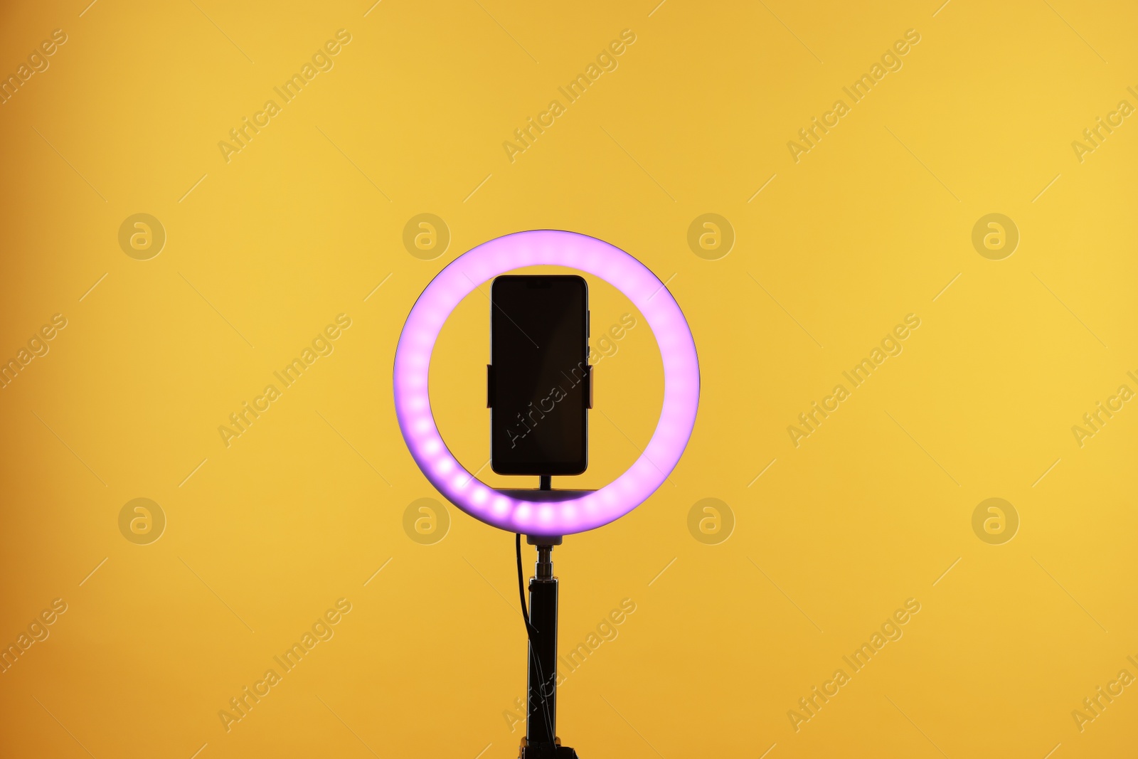 Photo of Ring lamp with smartphone on orange background