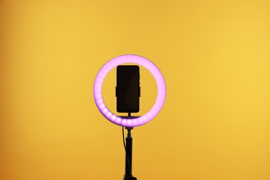 Photo of Ring lamp with smartphone on orange background