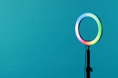 Photo of Ring lamp on stand against light blue background, space for text