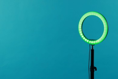 Photo of Ring lamp on stand against light blue background, space for text