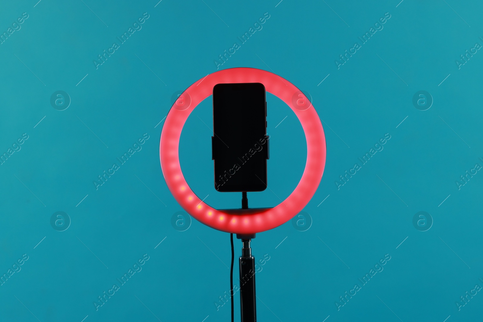 Photo of Ring lamp with smartphone on light blue background